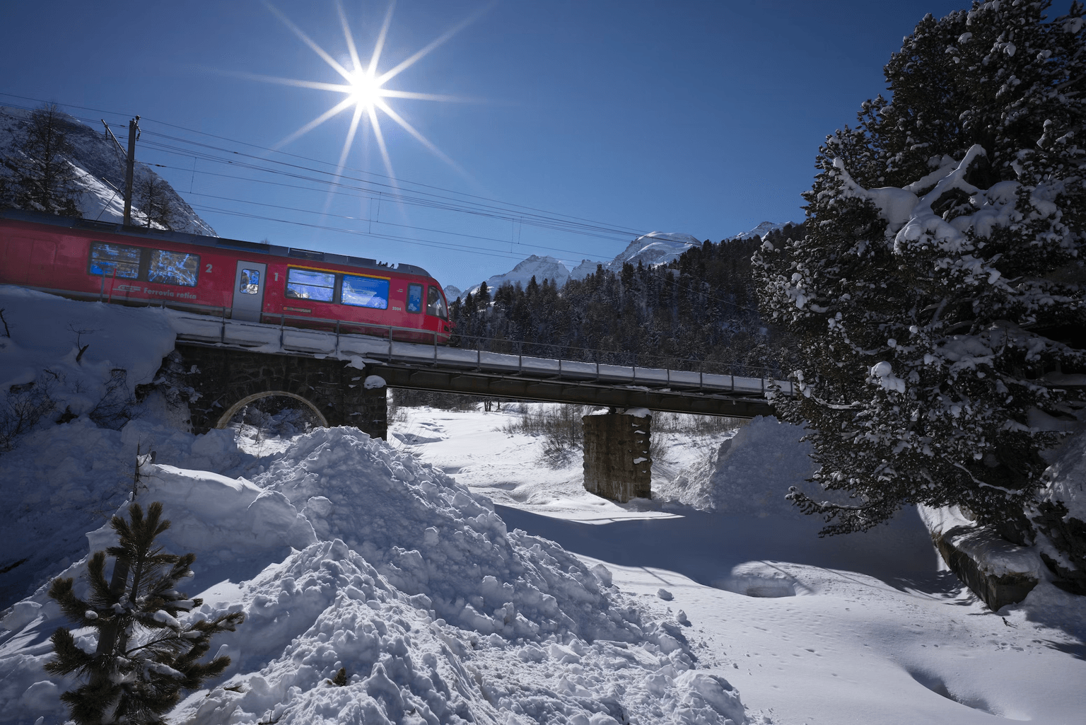Train over bridge in snowy but sunny setting